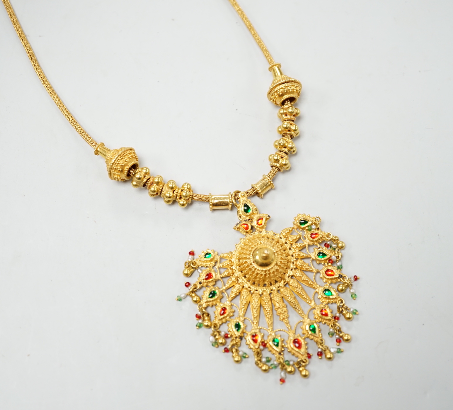 An Indian yellow metal two colour enamel and seed pearl set drop pendant necklace, overall, 45cm, gross weight 40.5 grams.
